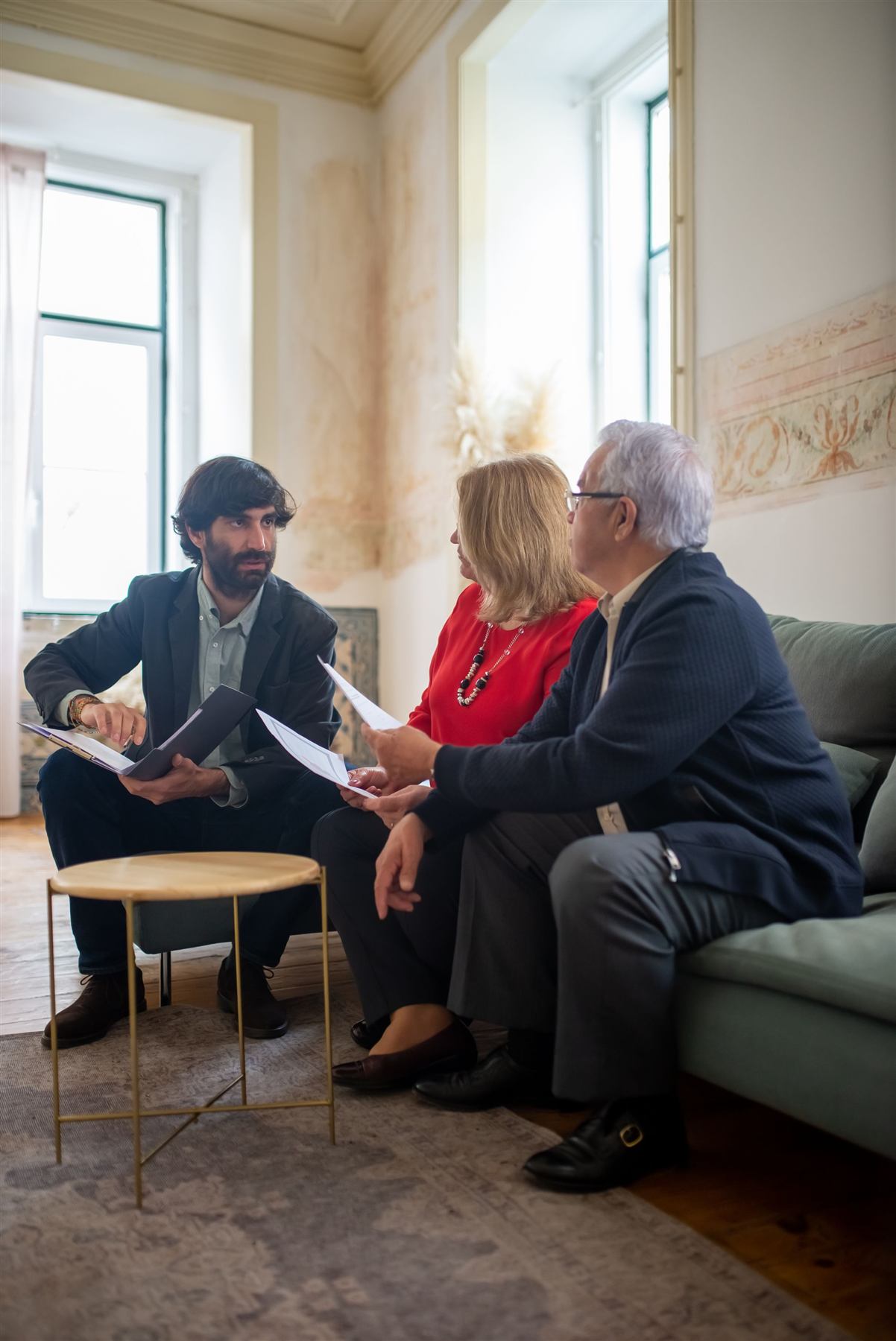 An advisor sitting with an older couple in their living room, going through their finances
