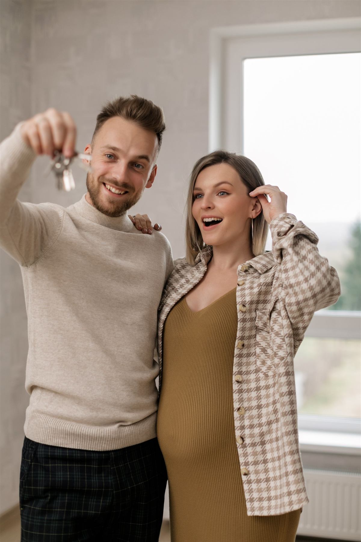 A smiling couple holding up the keys to their new home